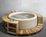 Ein heller Softub gefüllt mit Wasser mit einer hellen Holz Umrandung mit Beistellschränke