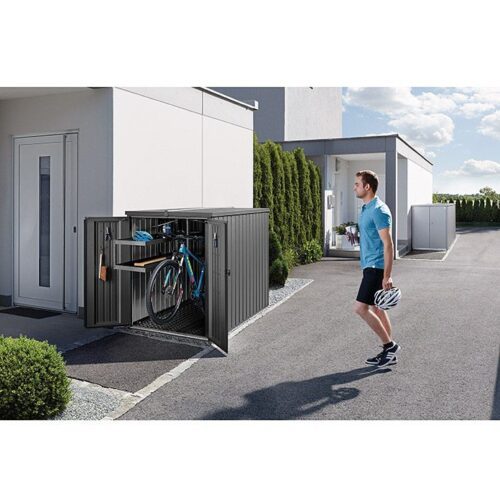 Abgebildet ist die Biohort MiniGarage. Sie ist geöffnet und steht neben einem Haus. Darin ist ein Fahrrad verstaut und ein Mann in einem blauen Tshirt steht daneben.