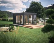 Dunkelgraues, modernes Gartenhaus und erweiterter Wohnraum mit Ganzglastüren, Fenstern und Flachdach in einem grossen Garten. Erweiterter Wohnraum kaufen Schweiz.