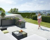 Das biohort DaVinci in dunkelgrau metallic auf einer grossen Terrasse mit Pool und Gartenlounge. Softub Schweiz