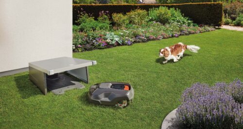 Le garage robot biohort Charly sur une pelouse. Le robot Charly se trouve devant.