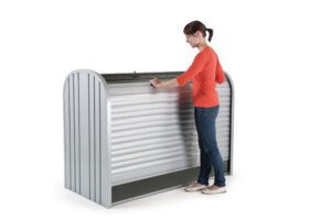 Biohort_StoreMax_oeffnen_Anwendungsbeispiel_Softub_Schweiz Frau steht vor einer silbernen Gartenbox und öffnet den Rollladen
