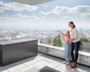 Gartenbox in quarzgrau metallic geschlossen auf einer Terrasse mit Ausblick auf eine Stadt.
