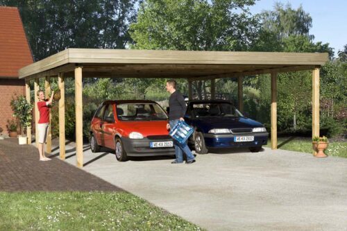 The Double Carport made out of wood from Weka. Stands infront of a house with a red and blue vehicle parked underneath
