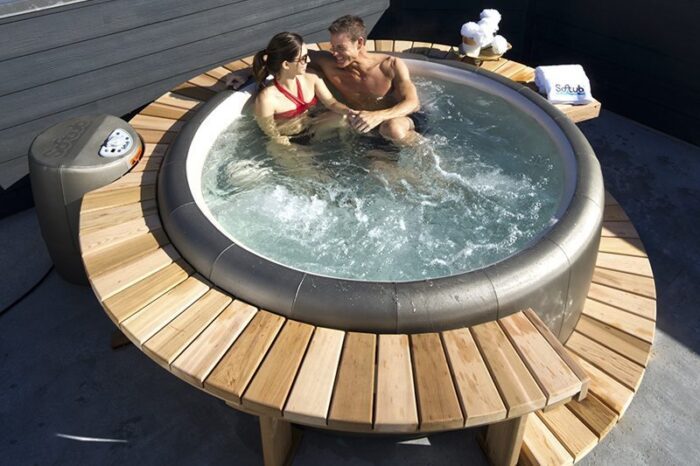 Softub whirlpool Portico. Dark grey whirlpool on a terrace, filled with water and wooden surround.