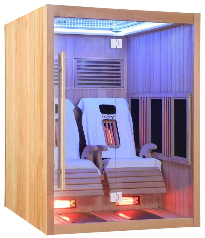 A bright infrared cabin made of wood. In the infrared cabin are two massage tables covered with two white towels.
