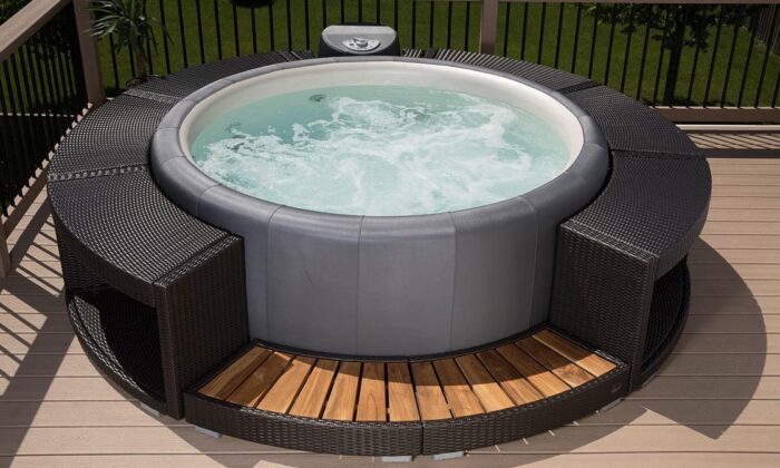 Outdoor whirlpool Softub Resort. Softub Resort with black polyrattan surround and steps.