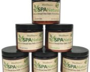 Sechs verschiedene kleine Töpfe mit schwarzen Deckel und beige Etikette, auf der Spa Naturals in einer hellen- und dunkelgrünen Farbe geschrieben steht.