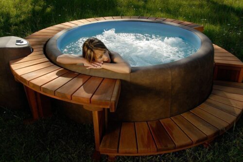 A woman is enjoying the Sportster Softub Whirlpool with a wooden frame