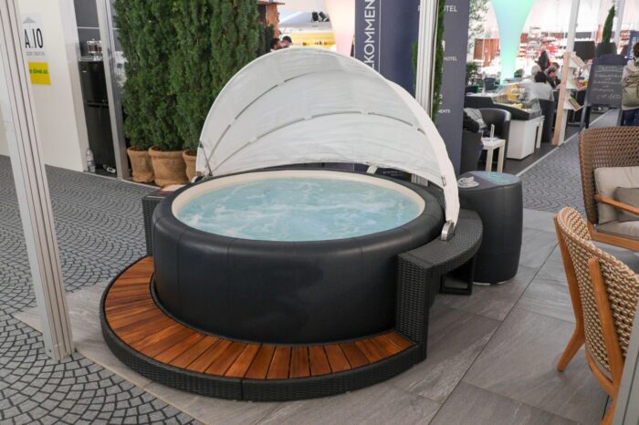 Umrandung aus Polyrattan mit Holztreppeneinstieg und weissem Sonnenschirm