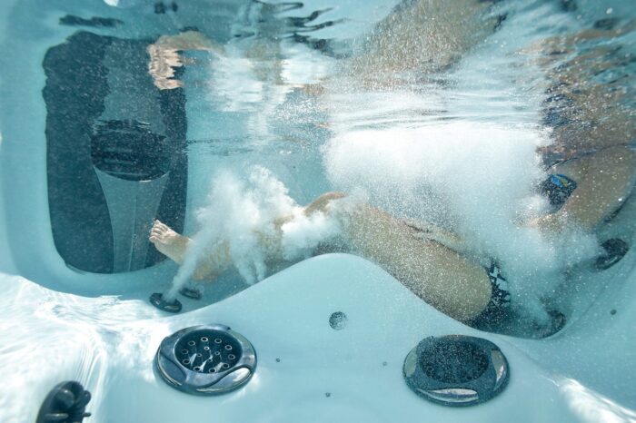 Unterwasserperspektive des Twilight Familienwhirlpools. Eine Person liegt in der Liege des Whirlpools.