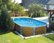 Massivholzpool von Weka. Grosser Weka Swimmingpool im Garten vor einem weissen Haus. Der Pool ist gefüllt mit zwei Kindern. Gartenausstattung Zubehör.