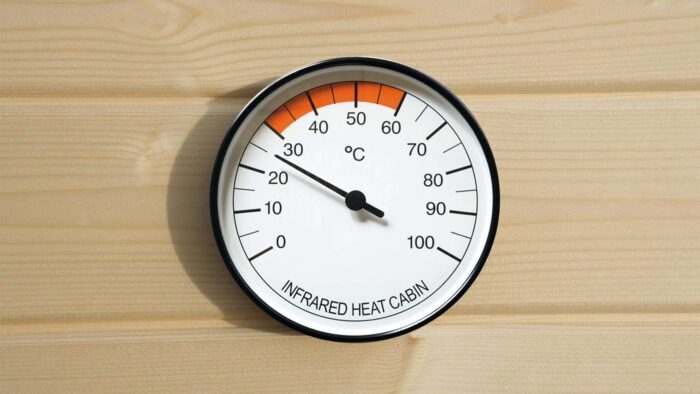Weka Thermometer für IR Kabinen. Eine weisser runder Thermometer an einer Holzwand angebracht.