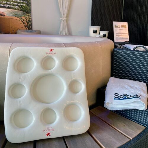 A white kool tray with eight dents for bottles and glasses. Kool Tray is on a polyrattan, wooden frame in front of a Softub and a Softub towel