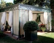 Der Unosider Pavillon Malatesta Plain mit weissen Vorhängen in einem grossen Garten.