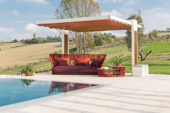 Der Unosider Pavillon Mood Balance mit roter Gartenlounge vor einem Pool. Das Dach ist geschlossen.