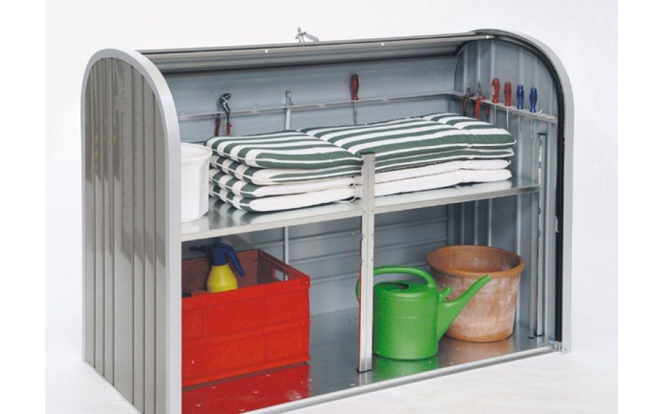 Offen stehende Gartenbox in silber mit Zwischenboden. In der Gartenbox sind Kissen, Werkzeuge, eine rote Kiste und eine grüne Giesskanne verstaut.