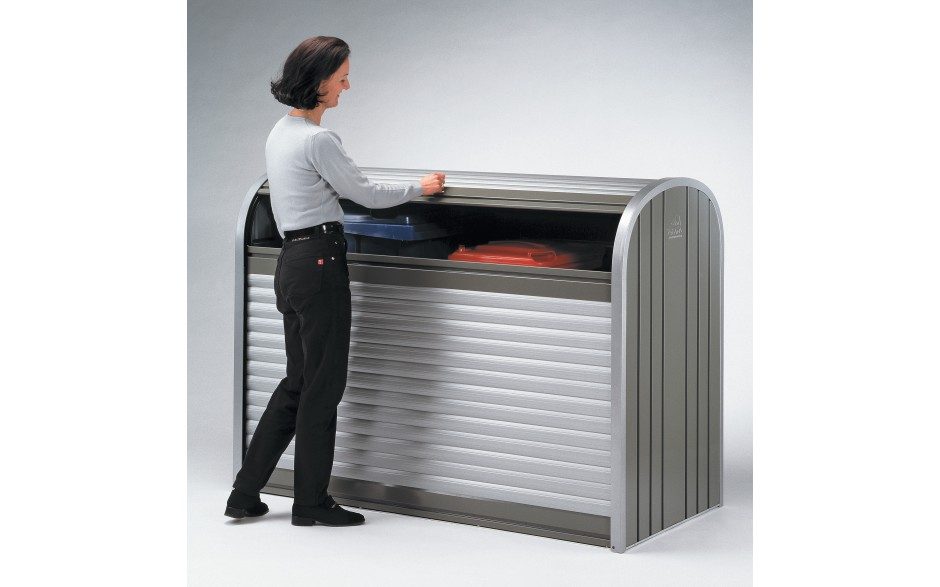 Eine Frau öffnet eine Gartenbox mit abgerundeten Ecken in Silber- und Grautönen. In der Gartenbox befindet sich ein blauer und roter Container.