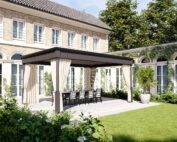 Unosider Pavillon Timeless Bioclimatica mit zusammengebundenen Vorhängen und grauem Dach vor einer grossen Villa in einem Garten.