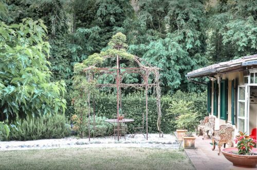 Unosider Pavillon Calicanto bedeckt mit Pflanzen in einem grünen Garten.