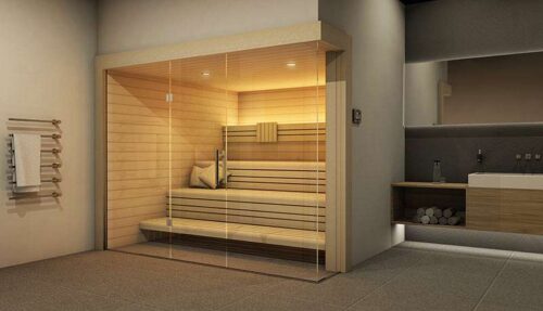 Sauna en bois clair avec bancs clairs. Intérieur éclairé par un éclairage indirect et une façade entièrement vitrée.